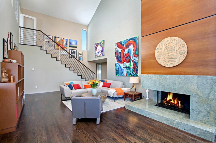 Belle cheminée allumée et salon aux tableaux multiples intérieur moderne tendance maison avec vue