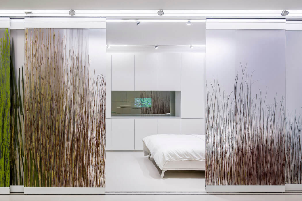 L’espace sommeil suit le même design ultra minimaliste où tous les rangements sont dissimulés chambre à coucher panneaux coulissants design luxe