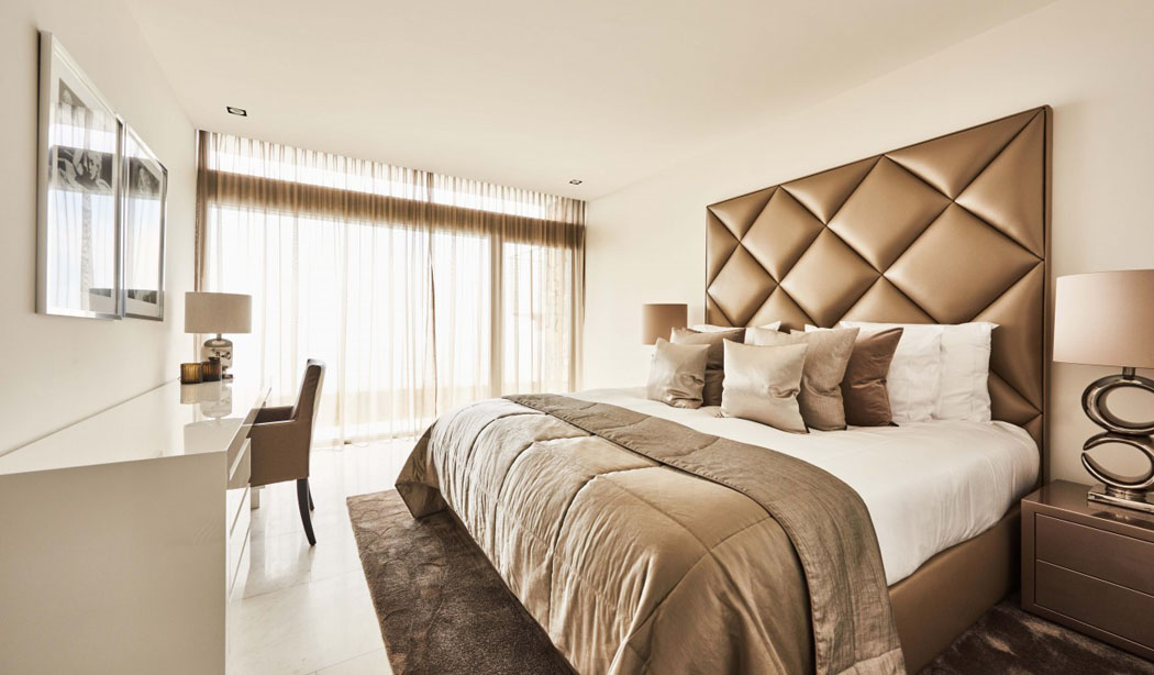 Une des chambres d’amis de cette maison secondaire s’inscrit également dans la prolongation beige – bronze du design intérieur tête de lit original capitonné chambre moderne