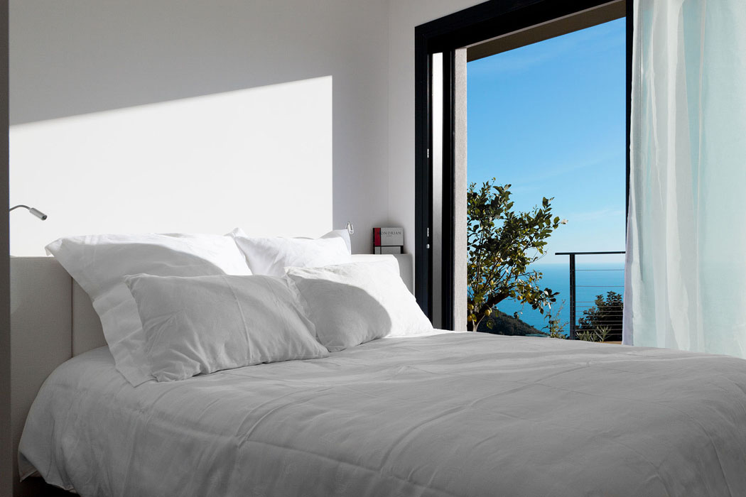 Chambre d’amis avec baie vitrée coulissante donnant sur la terrasse en bois lit double avec vue sur mer