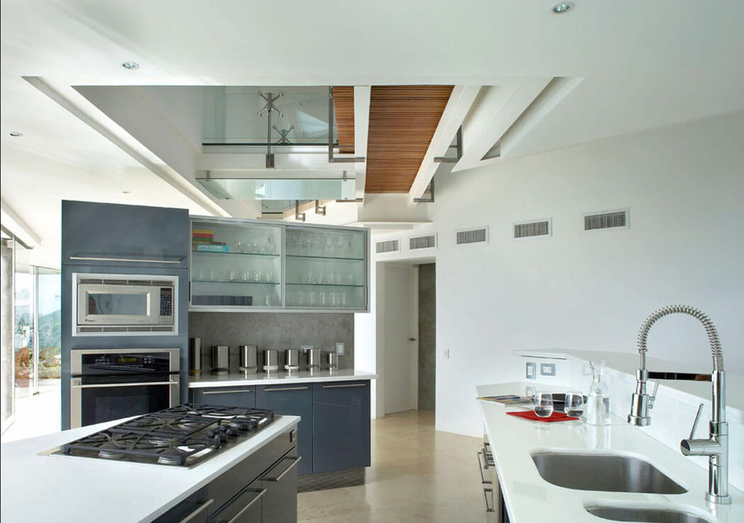 La cuisine est ouverte légèrement délimitée par un meuble haut où se trouvent le four et le micro-ondes cuisine équipée design déco villa de vacances maison secondaire
