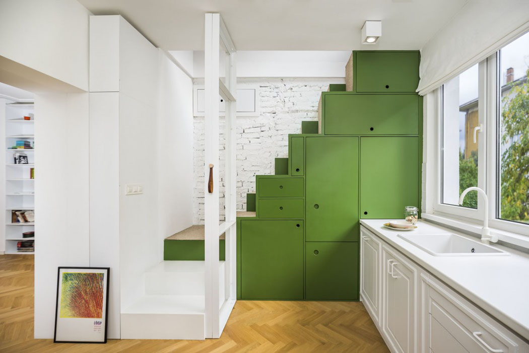 Optimisation de l’espace grâce aux nombreux rangements et murs en briques peints en blanc escalier cuisine ouverte placards blancs