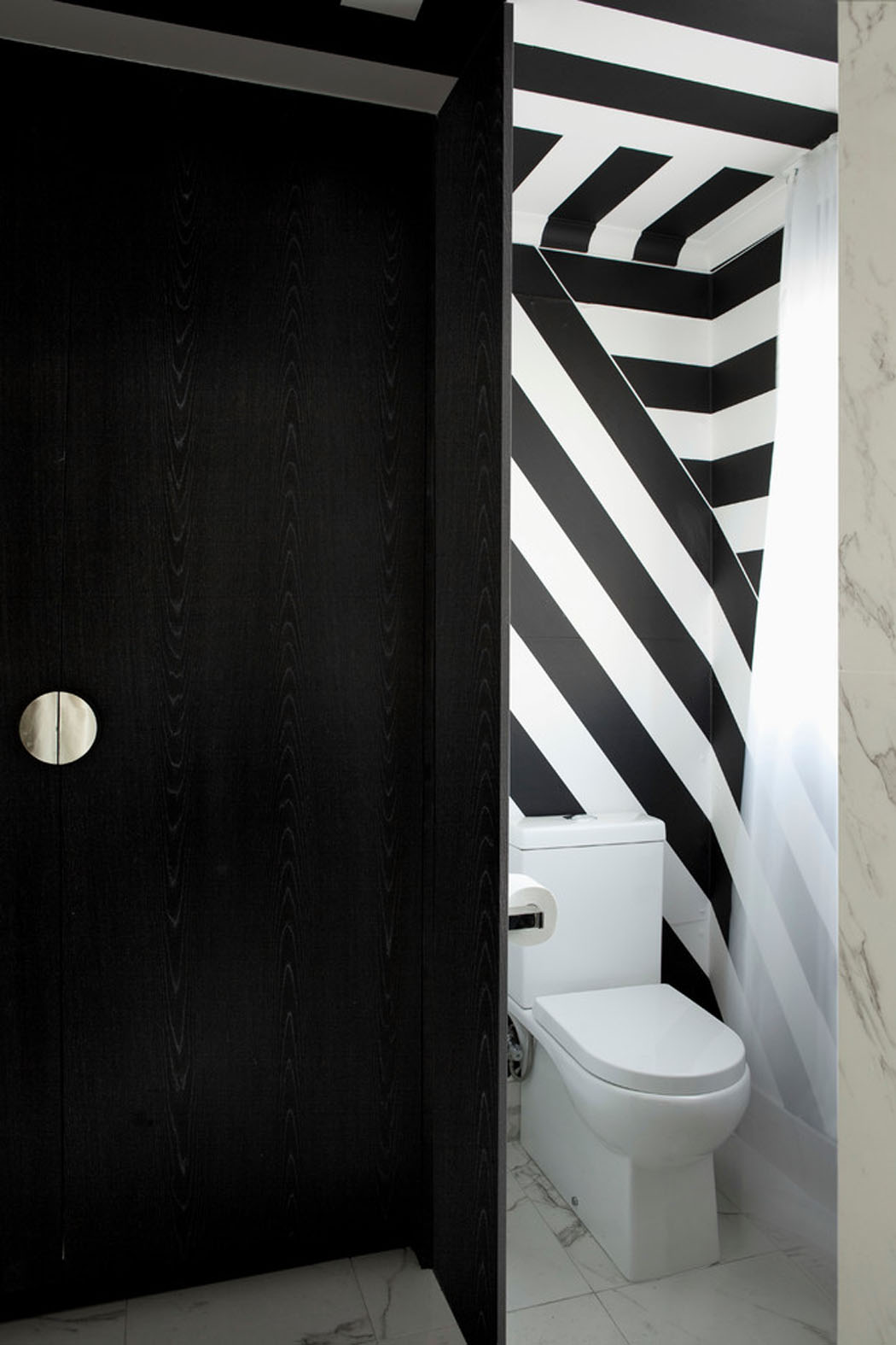 Les toilettes affichent une décoration qui suit la ligne de tout l’appartement design déco toilettes noir et blanc appartement design