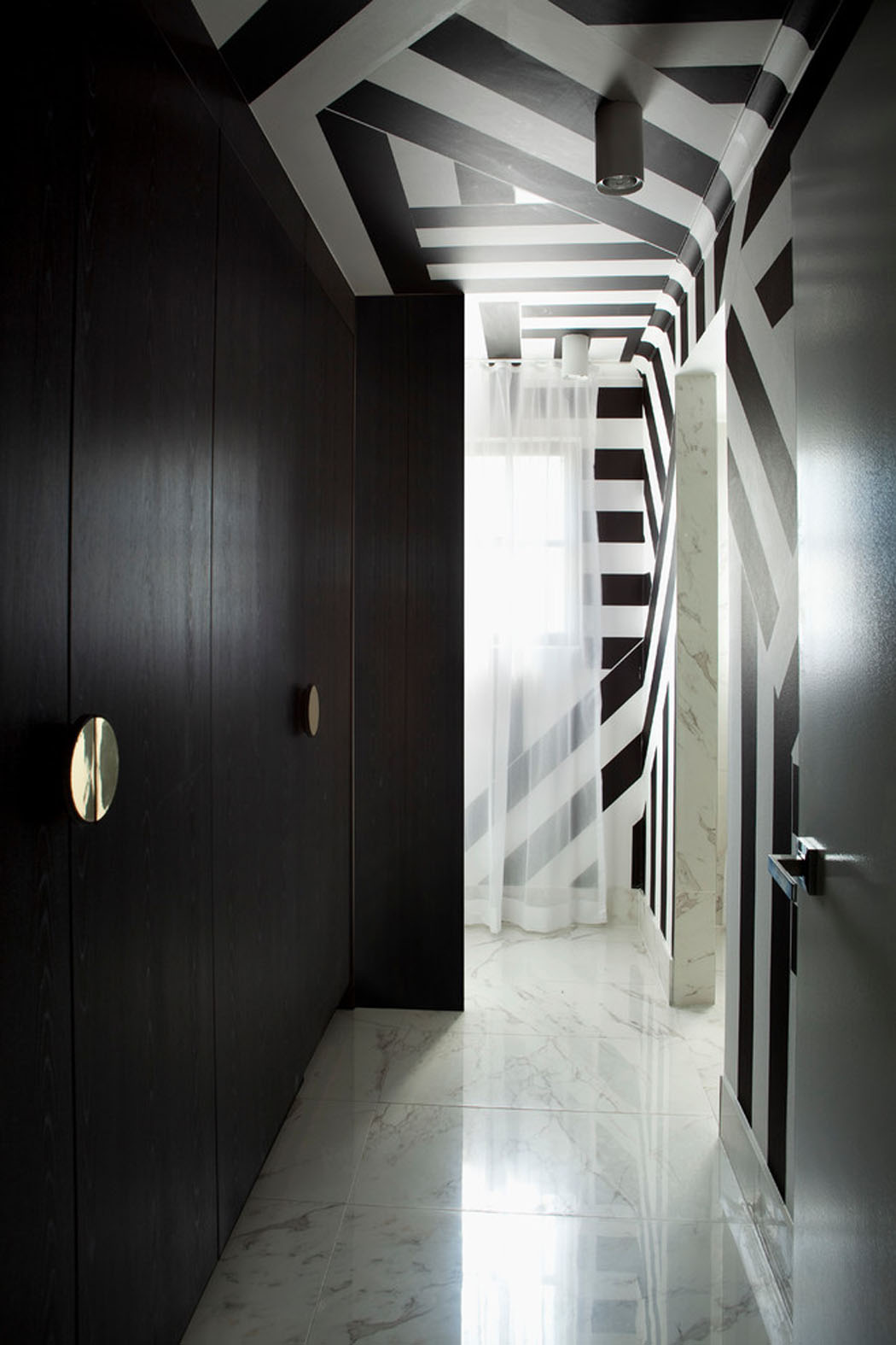 Le couloir de cet appartement design qui mène aux toilettes et à la salle de bains intérieur design chic appartement moderne