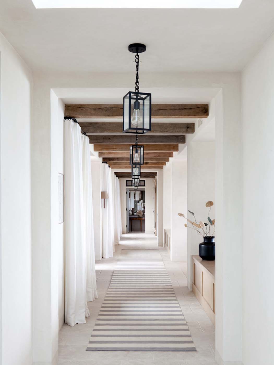 Le couloir en blanc souligne les éléments en bois massif et les luminaires en fer forgé intérieur éclectique couloir blanc