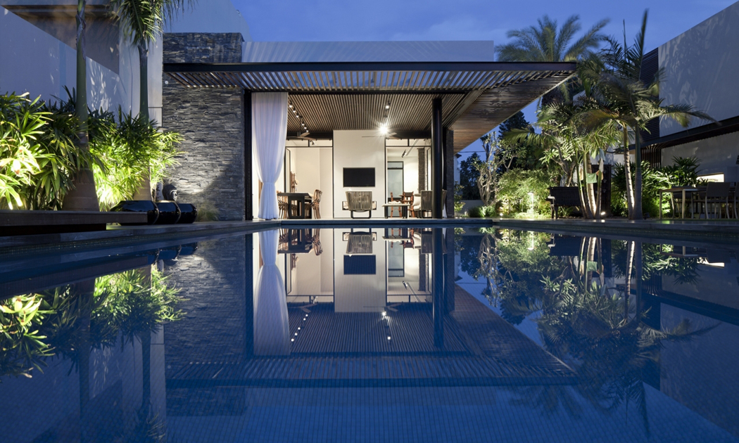 Vue sur cette jolie maison de ville éclairée dans la nuit à partir de la piscine maison de ville d'architecte vue depuis la piscine