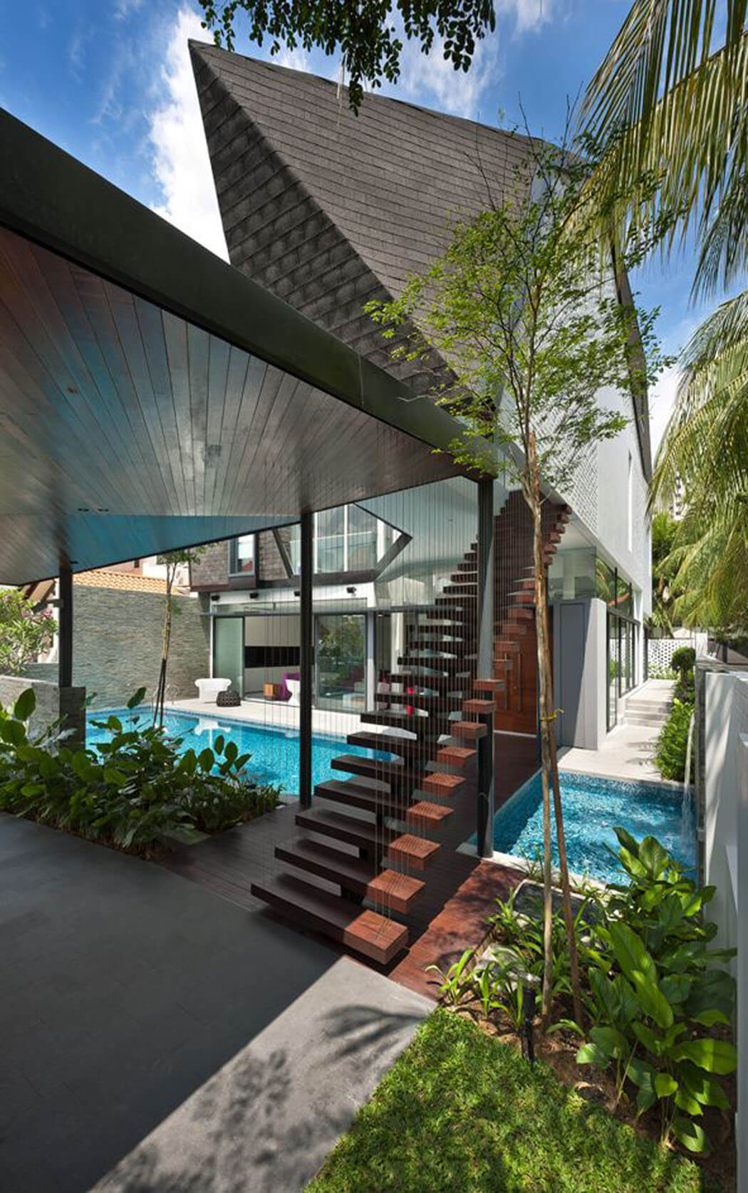 Un escalier design en bois exotique permet d’accéder directement à l’étage de cette maison rénovée agencement architecture originale maison originale singapour