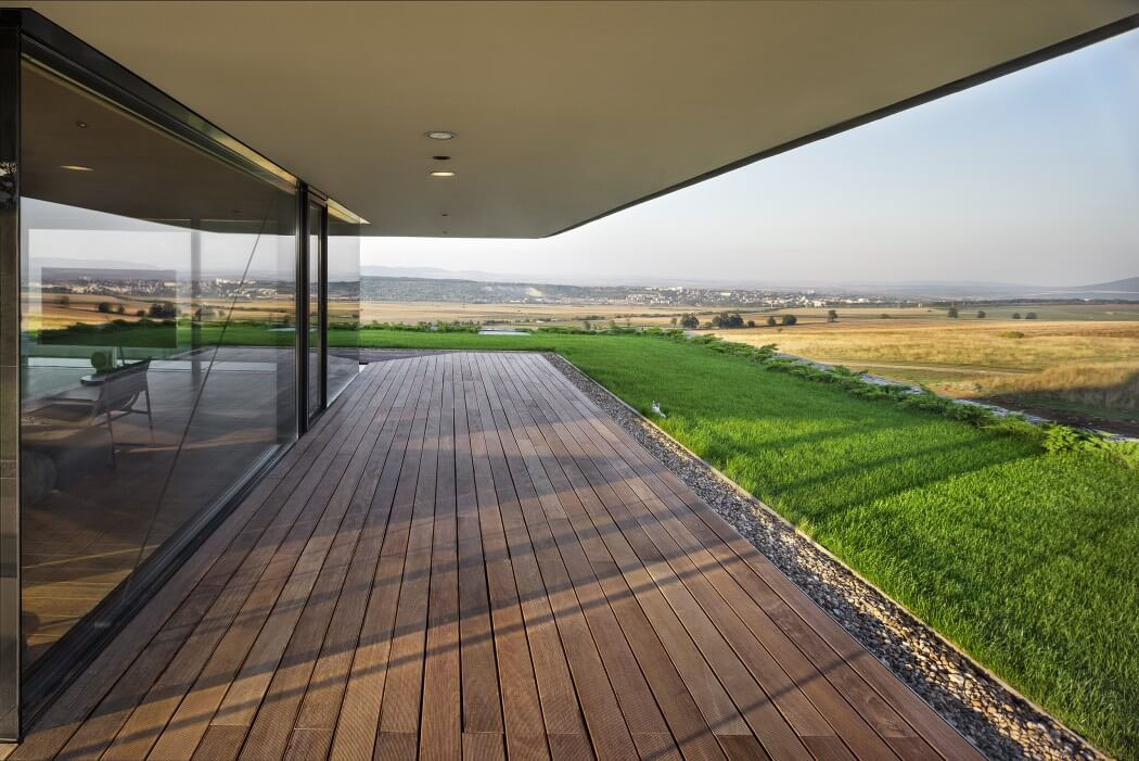 Terrasse couverte en bois devant de grandes baies vitrées de cette maison d’architecte belle demeure contemporaine d'architecte