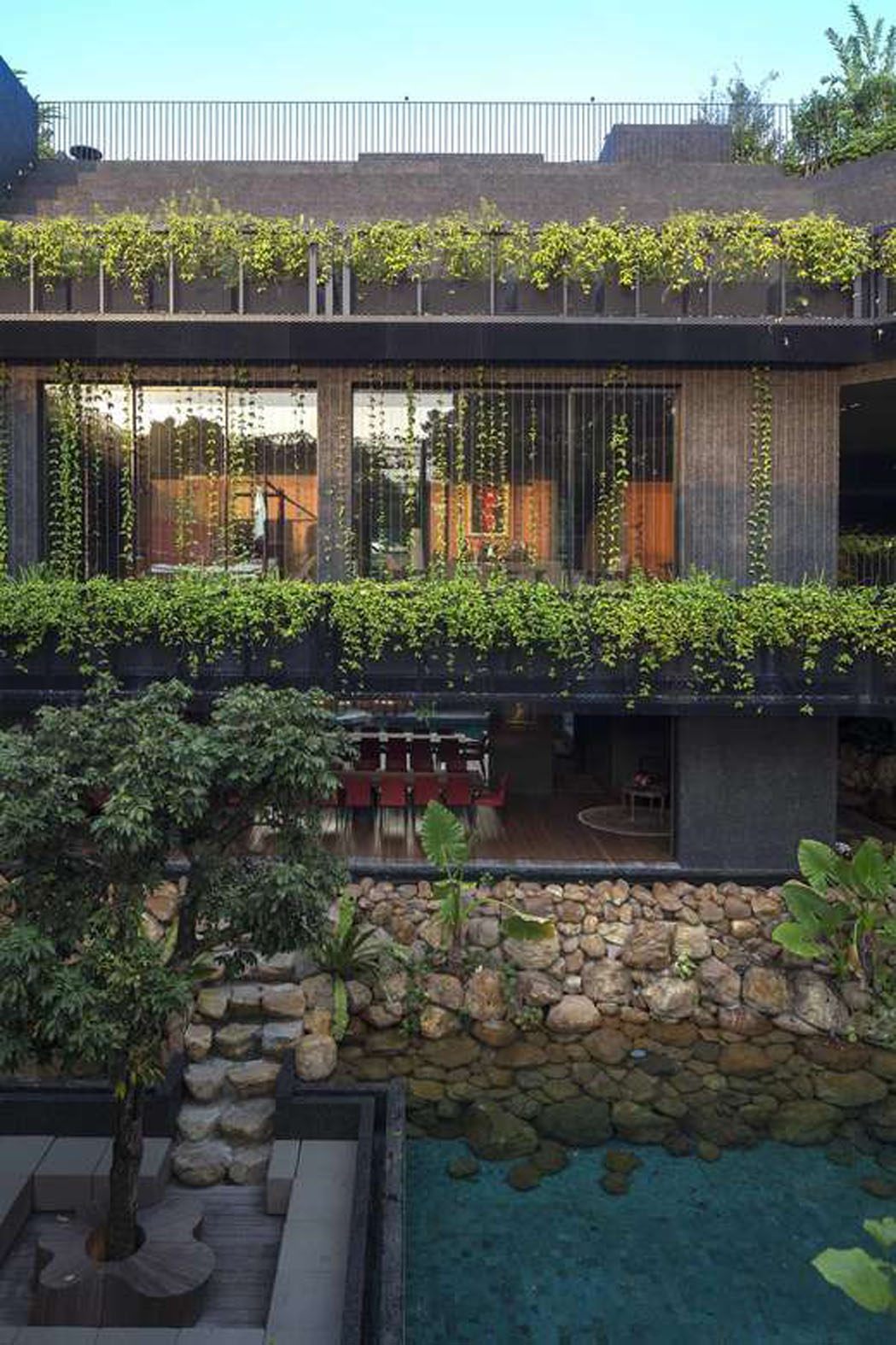 Le bois et les pierres se marient parfaitement avec les plantes vertes grimpantes de la façade architecture créative grande belle demeure écologique verte