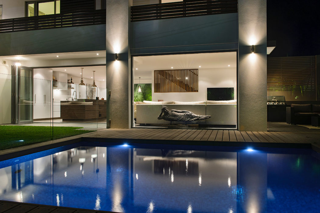 La piscine et la transformation de la pièce de vie principale à la tombée de la nuit grande piscine luxe design outdoor