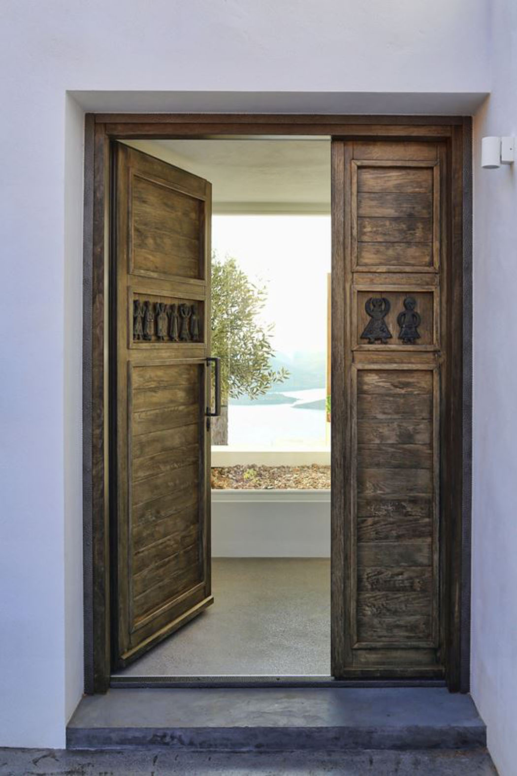 Porte d’entrée en bois massif donnant sur un jardin d’herbes aromatique menant vers la propriété située plus bas maison familiale de vacances à la côte mer Égée