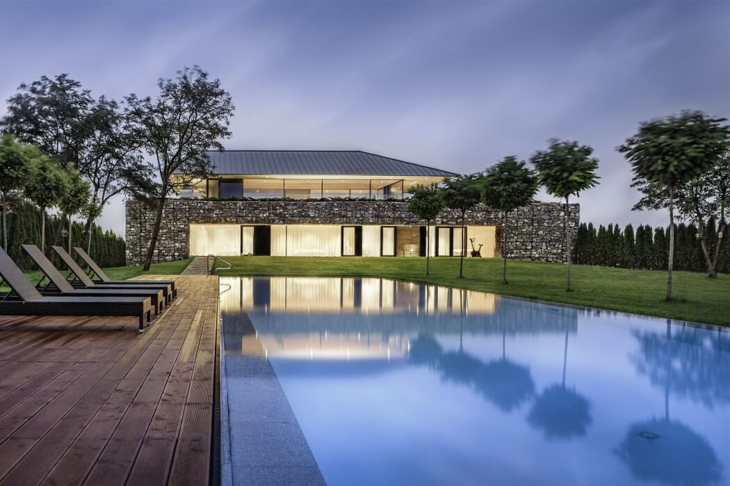 Vue de nuit depuis la piscine située au fond du jardin de cette belle maison d’architecte résidence contemporaine d'architecte moderne