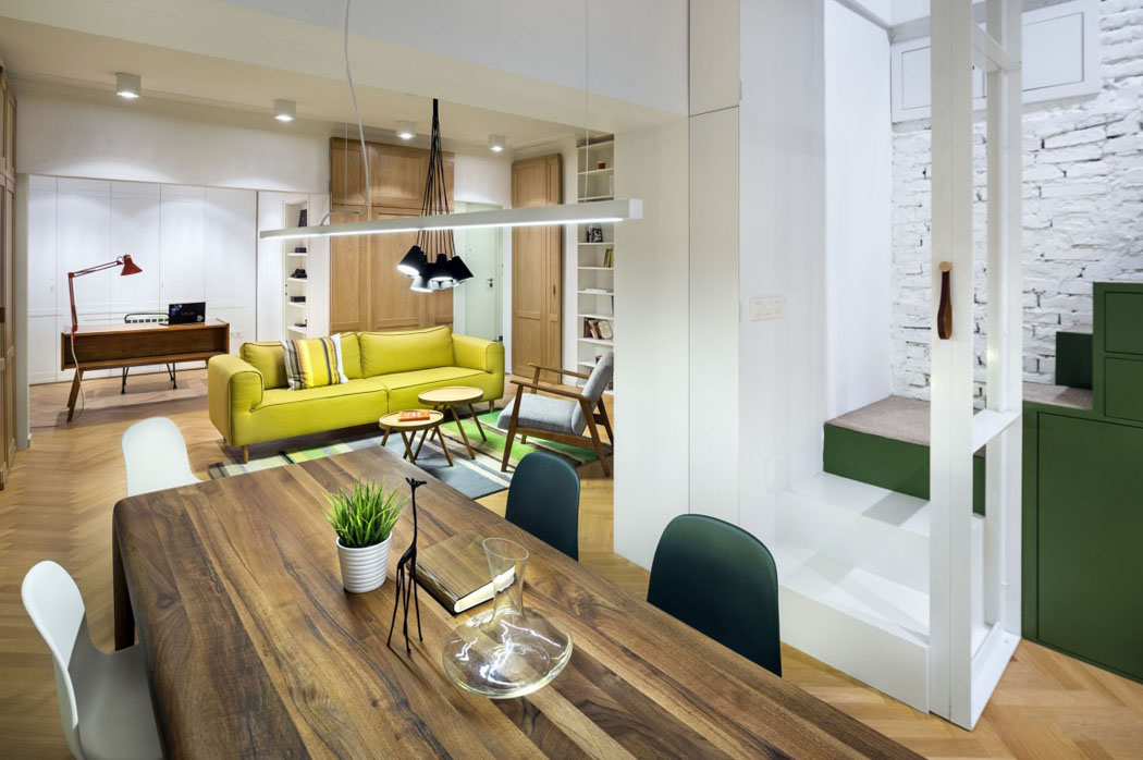 L’espace salle à manger aménagée comme un passage entre le salon et la cuisine ouverte grande table en bois salle à manger appartement moderne