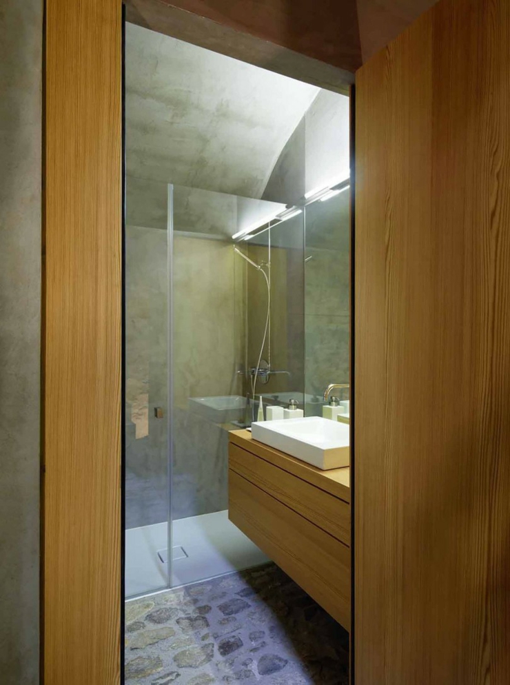 Salle de douche au sol en pierre et mur en béton douche bois et verre ancienne demeure