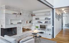 Une bibliothèque en marbre blanc et fabriquée sur mesure fait partie de l’ameublement design aménagement sobre appartement moderne en ville