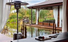 Le salon de la véranda entièrement vitrée qui se trouve au niveau de l’eau de l’étang véranda luxe agrandissement maison prestige