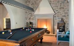 Une grande table de billard face à une belle cheminée pour passer d’agréables moments salle de jeux billard maison familiale rustique éclectique