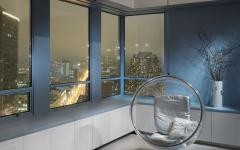 Fauteuil suspendu au design rétro des années 60 face aux grandes fenêtres donnant sur la ville mobilier design rétro intérieur maison