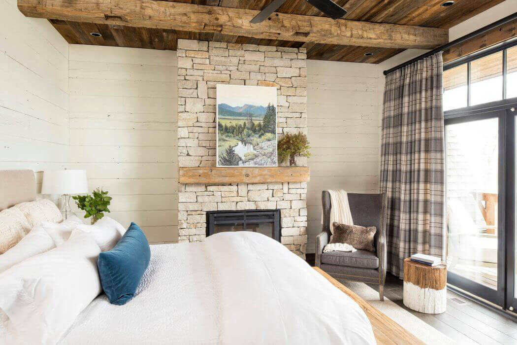 La suite parentale située à l’étage possède son propre balcon avec une jolie vue sur un paysage naturel chambre intérieur rustique maison secondaire campagne montagne