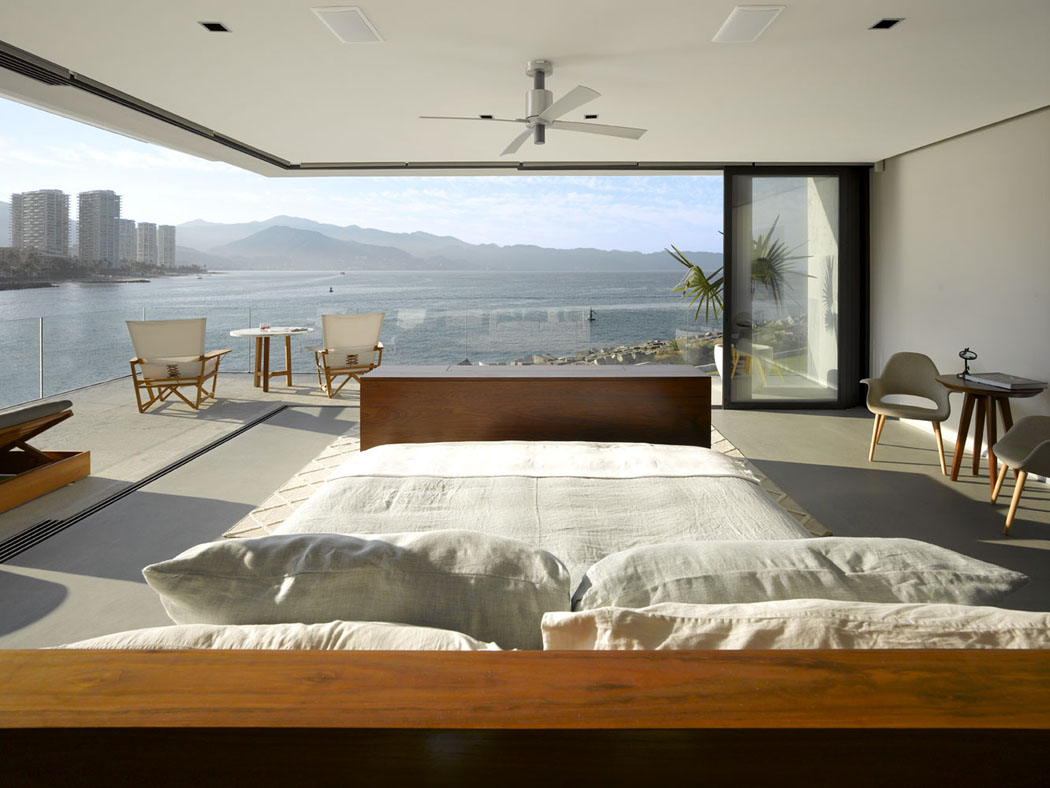 Une des chambres avec des énormes baies vitrées donnant sur un beau balcon et vue chambre principale avec vue mer