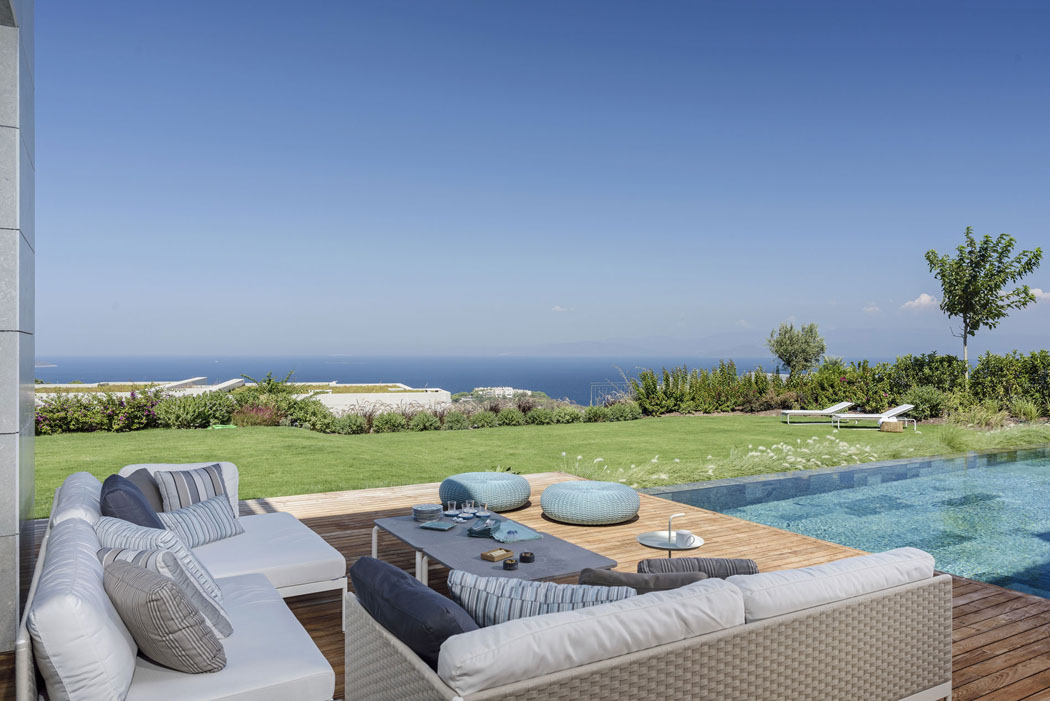 La terrasse en bois de la piscine et une partie du jardin découvrant une belle vue sur la mer piscine luxueuse extérieure jardin