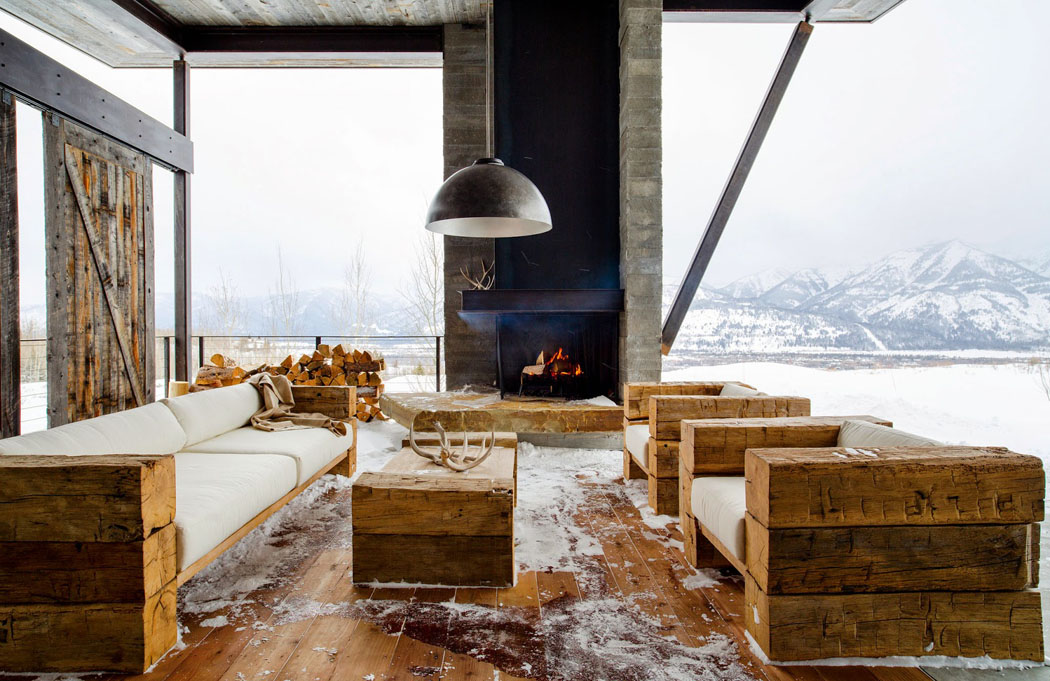 La terrasse avec la cheminée et mobilier en bois massif pendant l’hiver salon aménagé extérieur mobilier bois brut