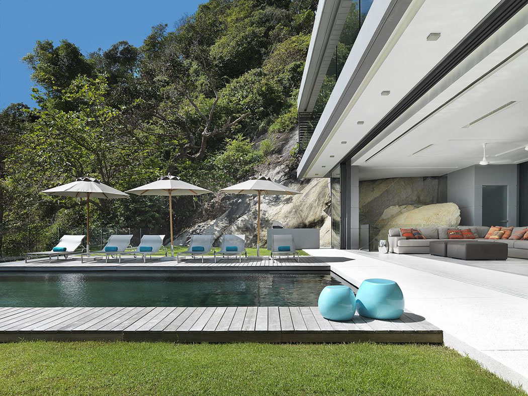 La terrasse autour de la piscine avec les chaises longues et les parasols pour passer d’agréables séances de bronzage terrasse piscine à débordement villa de luxe phuket
