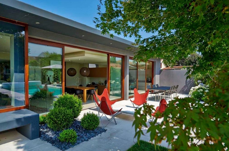 Terrasse accueillante entouré par un jardin vert et reposant demeure contemporaine plain-pied baie vitrée
