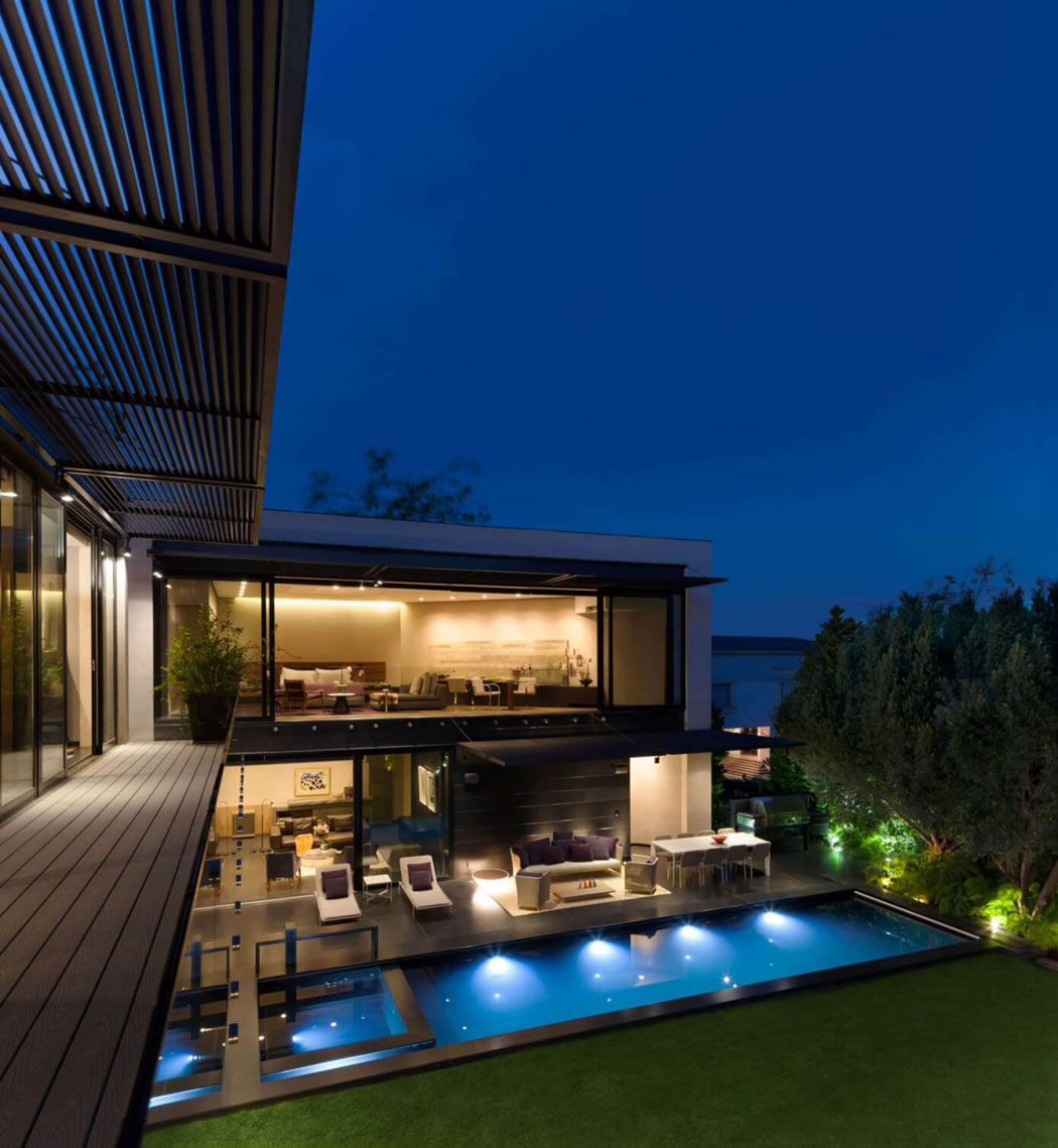 Les espaces outdoor avec la piscine et la grande terrasse éclairés dans la nuit piscine de luxe outdoor extérieure maison de ville