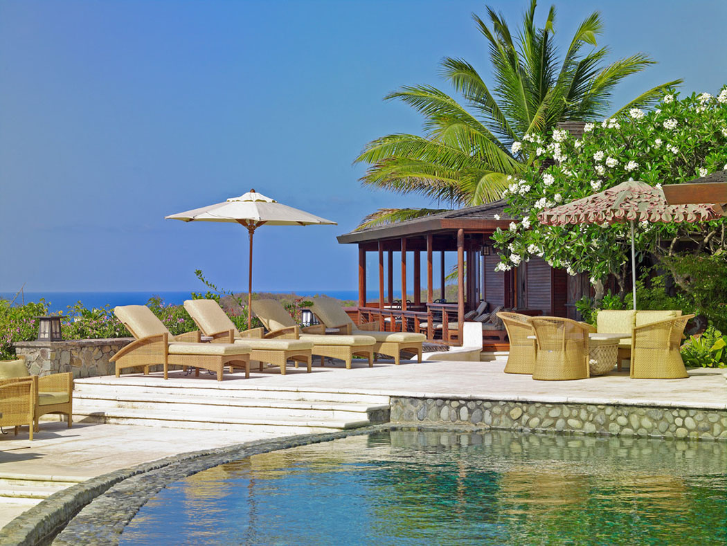 La terrasse donnant sur la plage et aménagée confortablement avec des chaises longues et fauteuils belle villa exotique sur la côte