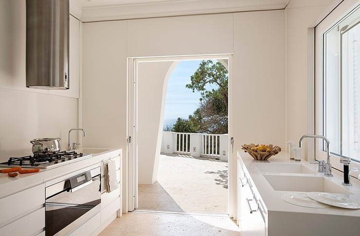 Cuisine tout en blanc à l’accès vers l’espace outdoor résidence secondaire moderne de luxe vacances italie